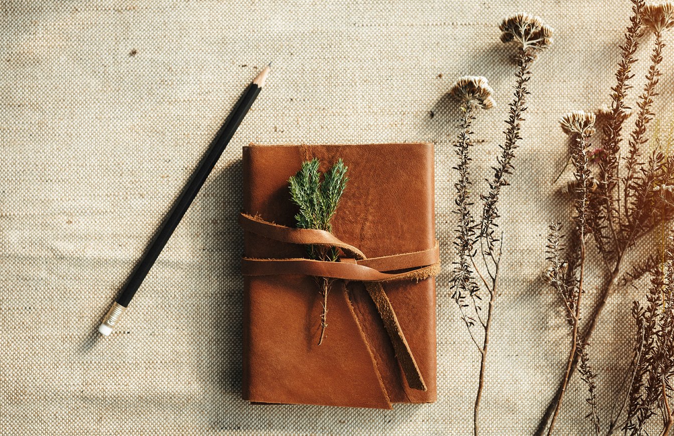 Leather personal journal with flowers on desk